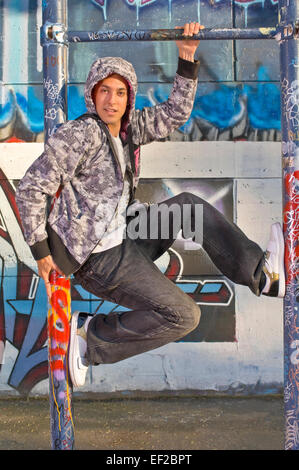 Adolescent en face d'un mur couvert de graffitis Banque D'Images