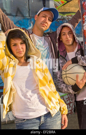 Trois adolescents posés devant un mur couvert de graffitis Banque D'Images