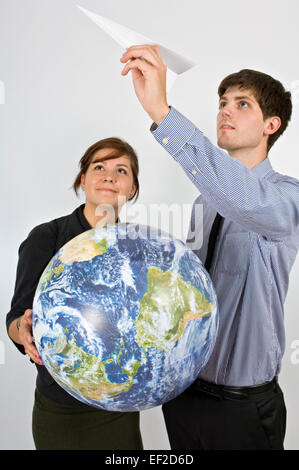 Deux personnes tenant un globe et un avion en papier Banque D'Images