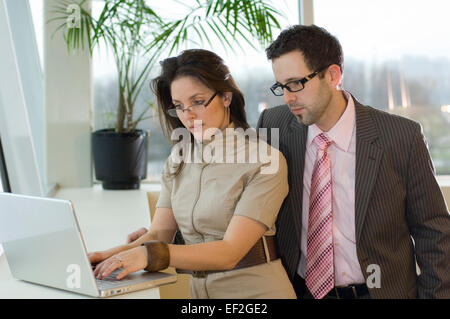 Bureau de collègues masculins et féminins looking at laptop computer Banque D'Images