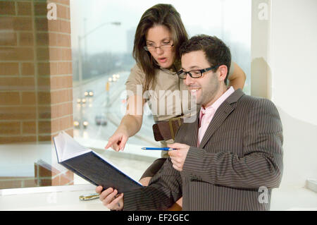 Les employés de bureau masculins et féminins l'examen livre de rendez-vous Banque D'Images
