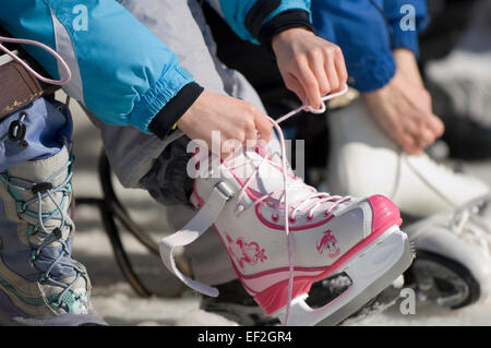 Jeune fille lacage des skates outdoors Banque D'Images