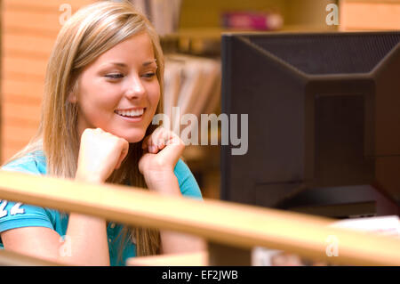 Jeune femme dans une bibliothèque à un terminal d'ordinateur Banque D'Images