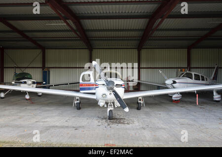 Vue avant du Mooney M20J 201 à l'intérieur de son hangar partageant l'espace avec deux Piper PA28 Banque D'Images