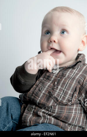 Bébé Garçon 9 mois, souriant, main dans la bouche Banque D'Images