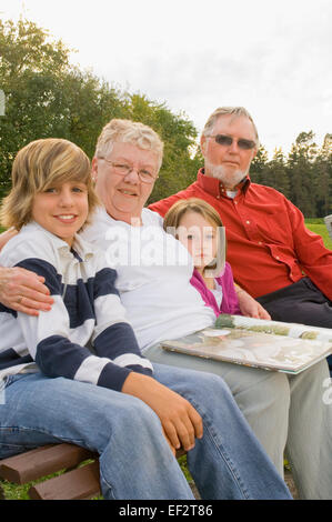 Les grands-parents et petits-enfants assis sur le banc de parc Banque D'Images
