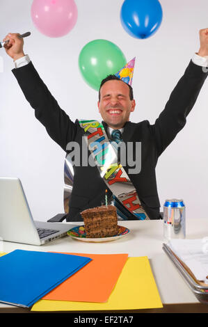 Excited businessman eating cake à son bureau. Banque D'Images