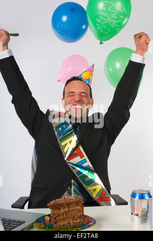 Excited businessman eating cake à son bureau. Banque D'Images