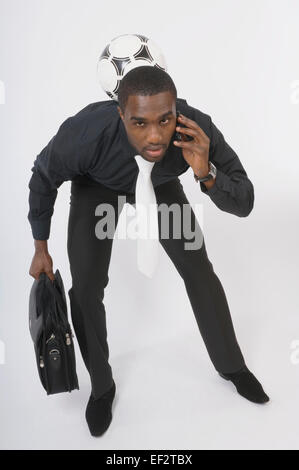 Businessman talking on the phone et jouer avec un ballon de foot Banque D'Images
