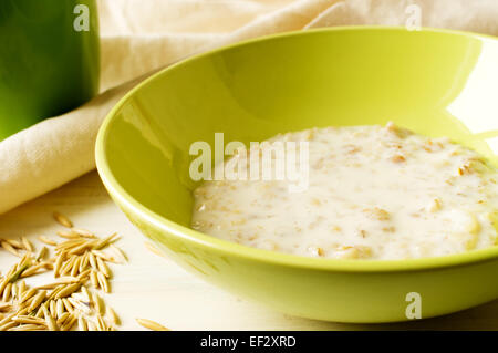 Le lait d'avoine dans un bol de porridge vert sur la table avec l'avoine Banque D'Images