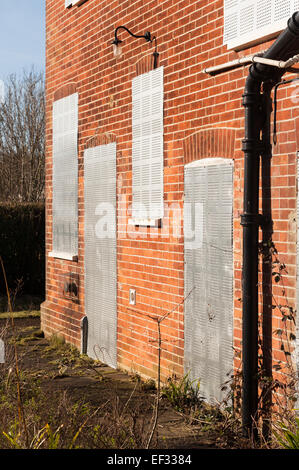 Maison individuelle dans un jardin luxuriant avec des feuilles de sécurité métalliques fermés pour éviter d'endommager les squatters entrée illégale de propriété Banque D'Images