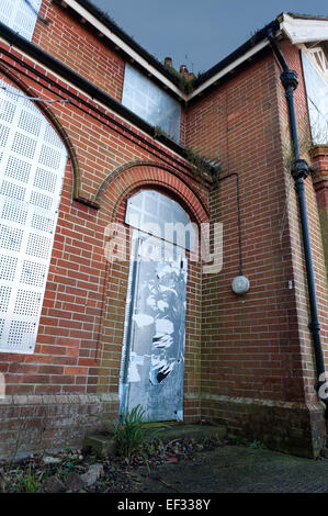 Maison individuelle dans un jardin luxuriant avec des feuilles de sécurité métalliques fermés pour éviter d'endommager les squatters entrée illégale de propriété Banque D'Images