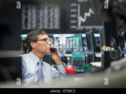 Un trader parle au téléphone sur le parquet devant le taux de l'indice boursier allemand DAX à la bourse de Francfort am Main, Allemagne, 26 janvier 2015. Malgré le résultat des élections en Grèce, la bourse allemande a continué son cours d'enregistrement sur le même jour. PHOTO : FRANK RUMPENHORST/dpa Banque D'Images