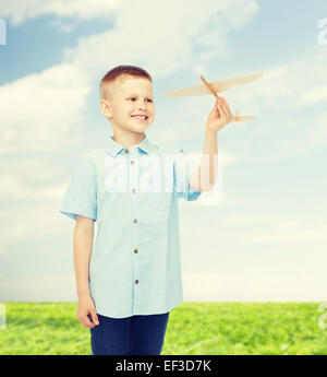 Smiling little boy holding un modèle d'avion en bois Banque D'Images