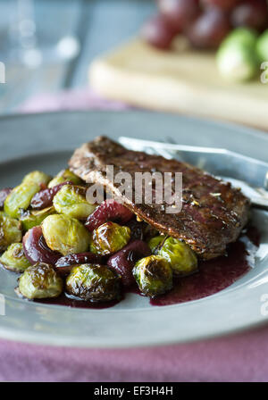 Rôti de boeuf aux flancs des choux de Bruxelles, les raisins et sauce au vin rouge Banque D'Images