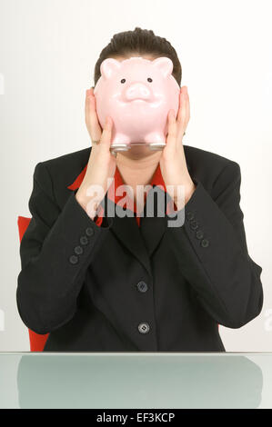 Businesswoman holding piggy bank en face de son visage Banque D'Images