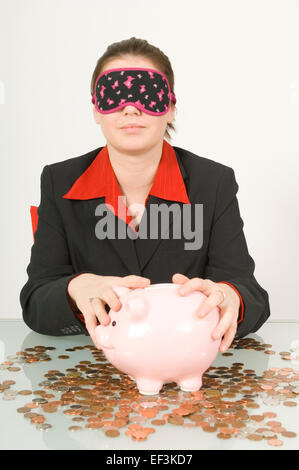 Les yeux bandés businesswoman holding a piggy bank Banque D'Images