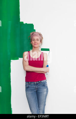 Une femme debout devant un mur qui a été peint avec la couleur verte elle-même Banque D'Images