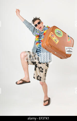 Heureux homme portant Hawaiian lei et transportant suitcase Banque D'Images