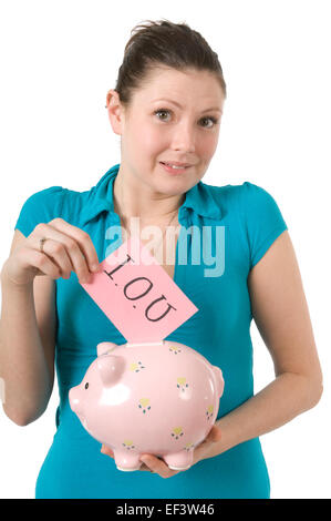 Woman putting I.O.U. card in piggy bank Banque D'Images