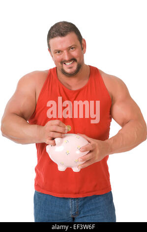 L'homme musclé mettant coin in piggy bank Banque D'Images