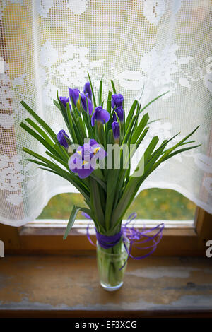 Purple iris fleurs dans un vase, sur la table en bois Banque D'Images