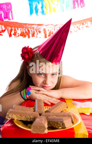 Geste ennuyé kid girl blonde en partie avec des chocolats et anniversaire hat Banque D'Images