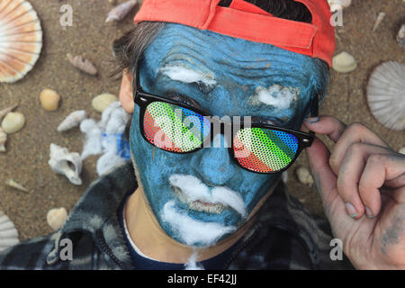 L'homme fou avec face bleue portant des lunettes arc-en-ciel Banque D'Images