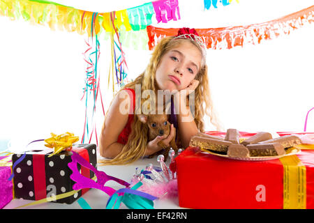 Geste ennuyé kid girl blonde en partie avec des chocolats et chiot chihuahua dog Banque D'Images