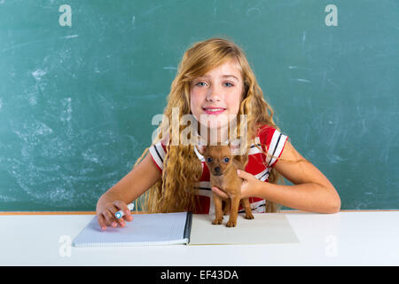 Fille étudiante blonde avec petit chien au bord de la craie verte classe assis dans 24 Banque D'Images