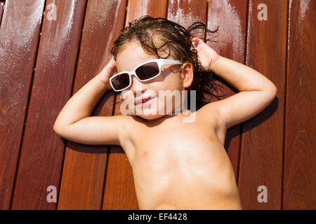 Bébé Enfant kid en été vacances soleil Bronzage sur pont en teck en bois Banque D'Images