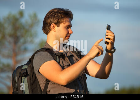 Jeune homme de travail touristique avec le smartphone à l'extérieur de voyage. Route de la recherche dans le navigateur ou de faire des photos de l'emplacement. Banque D'Images