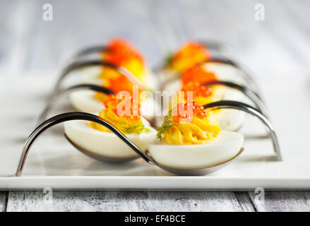 Oeufs farcis avec du caviar rouge dans une cuillère Banque D'Images