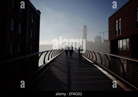 Silhouettes de piétons et des coureurs au London's Millennium Bridge sur un matin brumeux avec la Tate Modern visible en arrière-plan. Banque D'Images