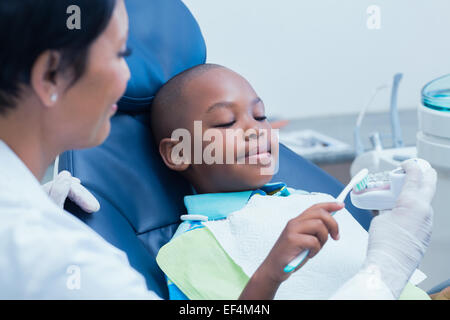 Dentiste femme garçon enseignement comment brosser les dents Banque D'Images