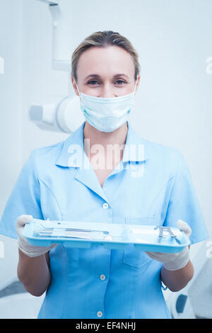 Femme dentiste dans un masque chirurgical holding tray of tools Banque D'Images