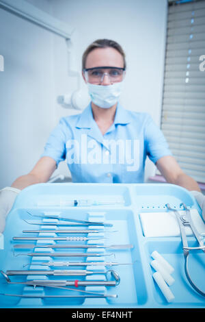 Femme dentiste dans un masque chirurgical holding tray of tools Banque D'Images