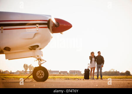 Jeune couple sur l'aérodrome, avion à hélice en premier plan Banque D'Images