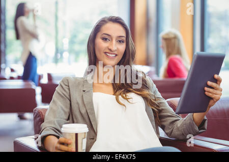 Smiling girl using digital tablet et holding disposable cup Banque D'Images