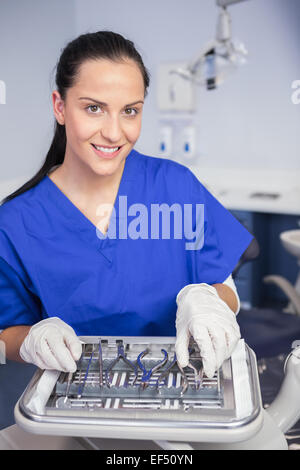 Smiling dentiste ramasse un outil sur le plateau Banque D'Images