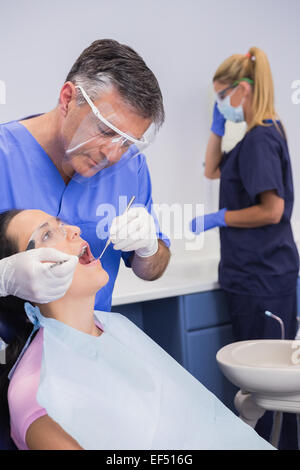 Dentiste portant un masque et examinant un patient Banque D'Images