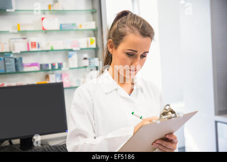 Pharmacien Junior writing on clipboard Banque D'Images