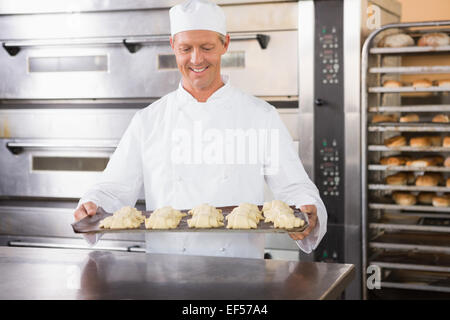 Smiling baker holding tray of pâte crue Banque D'Images