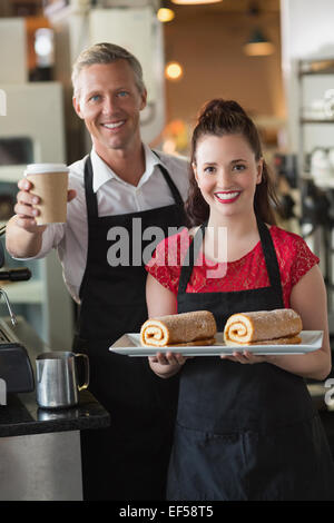 Waitress smiling at the camera montrant des gâteaux Banque D'Images