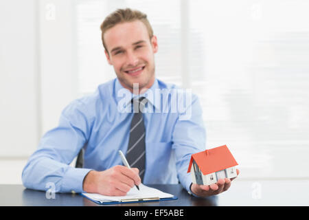 Businessman taking notes et montrant miniature house Banque D'Images