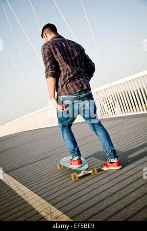 Jeune homme skateboarding sur bridge Banque D'Images