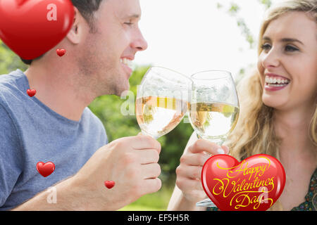 Image composite de cheerful couple toasting with white wine Banque D'Images