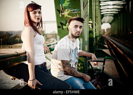 Jeune couple avec Skateboard and BMX bicycle outdoors