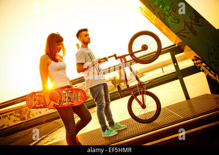 Jeune couple avec Skateboard and BMX bicycle outdoors