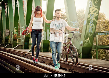 Jeune couple avec Skateboard and BMX bicycle outdoors